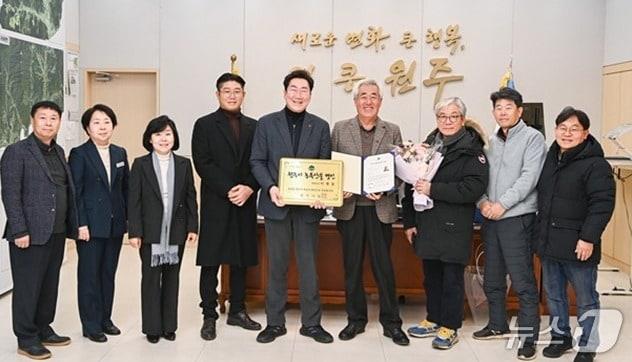 본문 이미지 - 강원 원주시 소초면에서 농가를 운영 중인 이병동 씨(오른쪽에서 네 번째)가 최근 원주시청에서 시의 초대 농특산물 명인임을 인정하는 인증서와 인증패를 받은 가운데, 원강수 원주시장을 비롯한 시 관계자들과 시장 집무실에서 기념 사진을 촬영하고 있다. (원주시 제공. 재판매 및 DB 금지) 2025.12.30/뉴스1