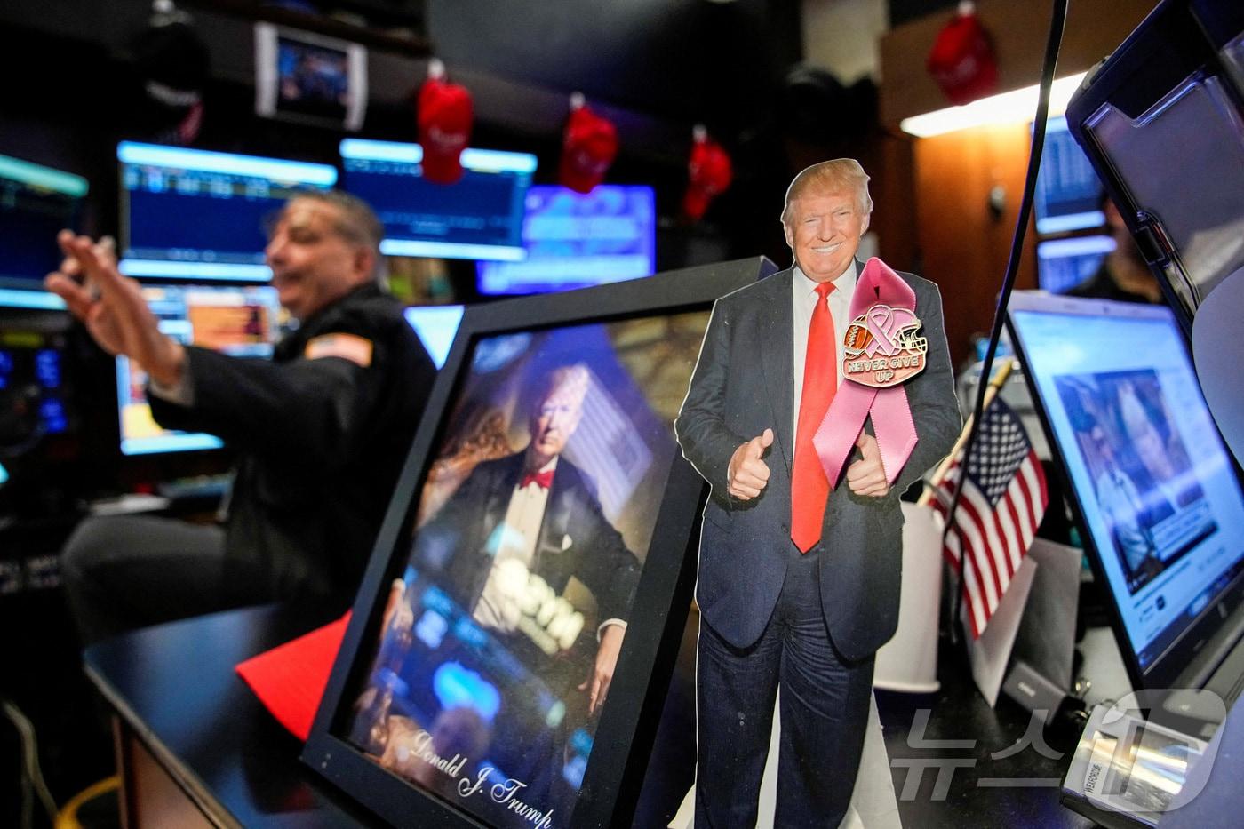 2025년 12월 2일 뉴욕증권거래소(NYSE)에서 도널드 트럼프 대통령의 사진 뒤로 한 트레이더가 분주하게 업무를 보고 있다. ⓒ 로이터=뉴스1