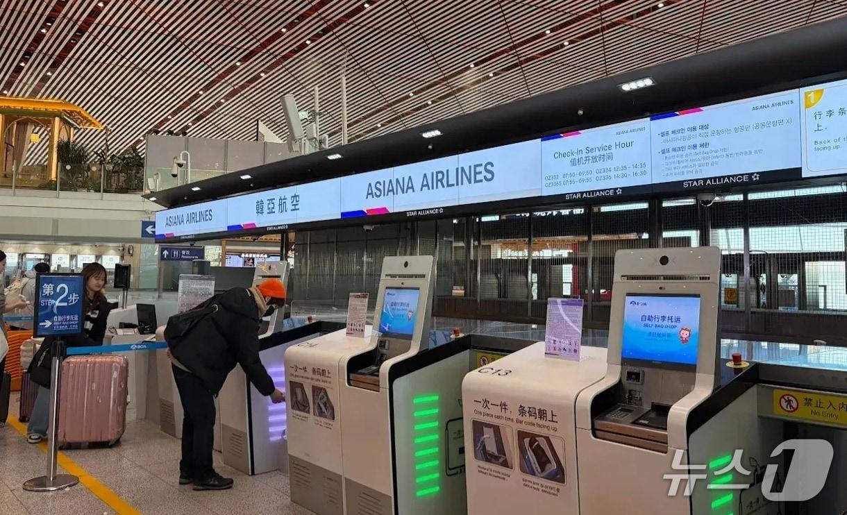 본문 이미지 - 30일 중국 베이징공항 제3터미널에 아시아나항공 셀프 체크인 서비스를 돕는 탑승권 키오스크와 셀프 백드롭 기기가 놓인 모습(아시아나항공 제공). 2025.12.30.