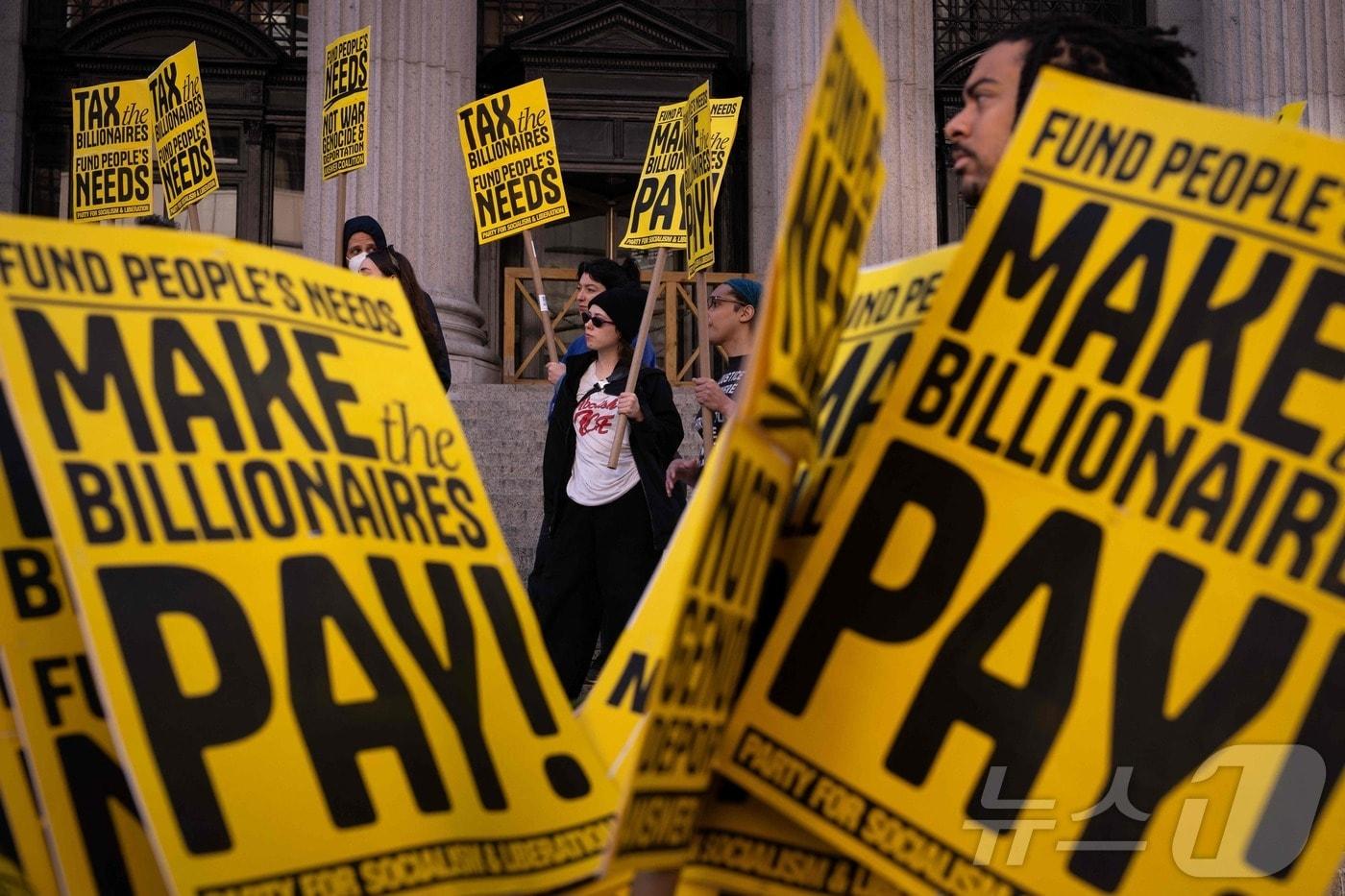 2025년 4월 15일, ‘세금의 날’을 맞아 뉴욕시에서 시위대가 억만장자들에게 더 많은 세금을 부과하라고 요구하며 집회를 열었다. 활동가들은 보편적 의료, 무상 대학 교육, 그리고 기아와 노숙 문제 해결을 위해90% 부유세를 도입해야 한다고 주장했다.2025.04.15.ⓒ AFP=뉴스1