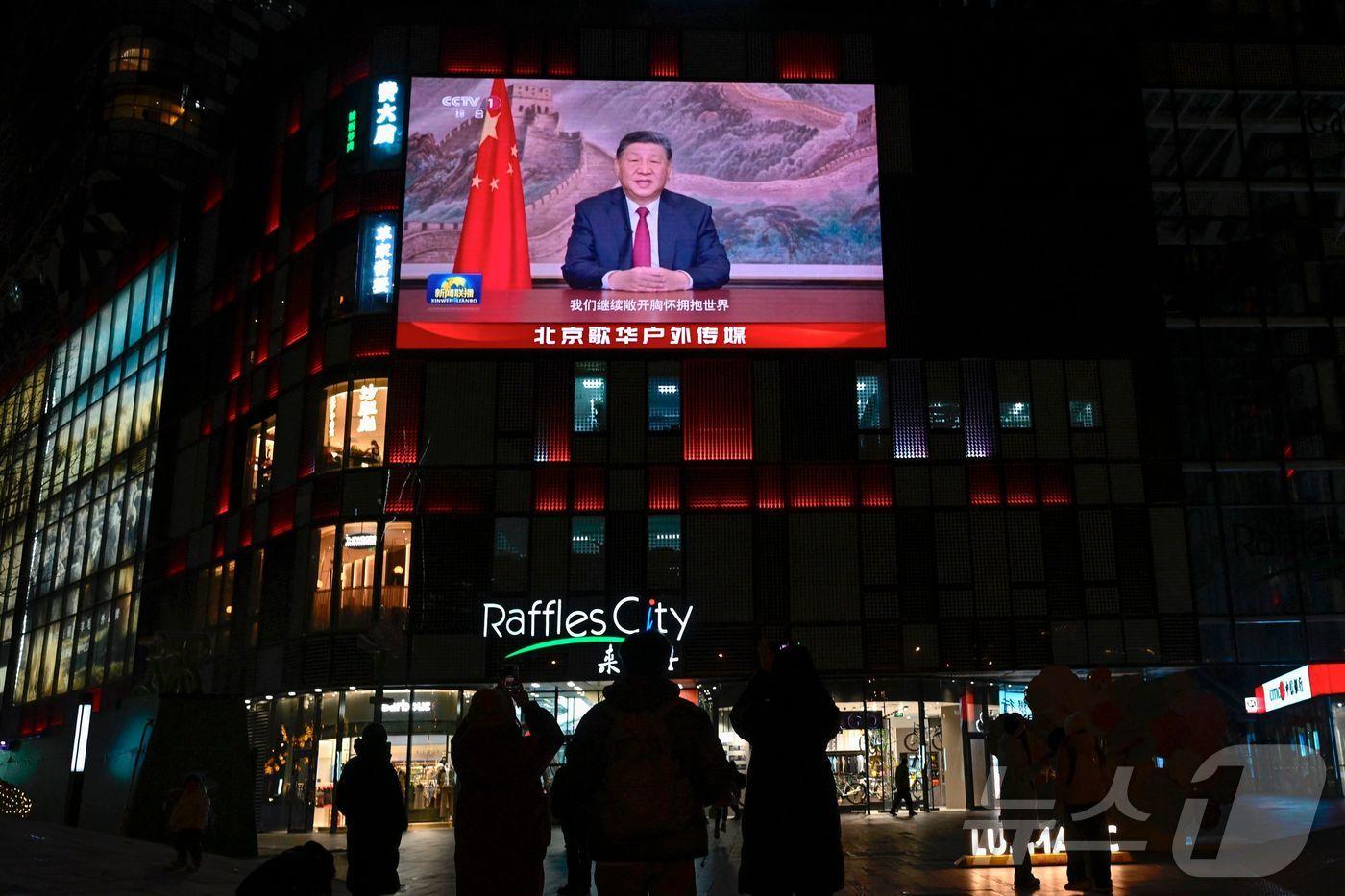 2025년 12월 31일 베이징에서 열린 새해 전야 행사 직전, 대형 스크린 아래에 시민들이 모여 시진핑 중국 국가주석의 연설을 지켜보고 있다. 시 주석은 이날 연설에서 “통일은 멈출 수 없다”며 대만과의 통일 의지를 피력했다.2025.12.31.ⓒ AFP=뉴스1