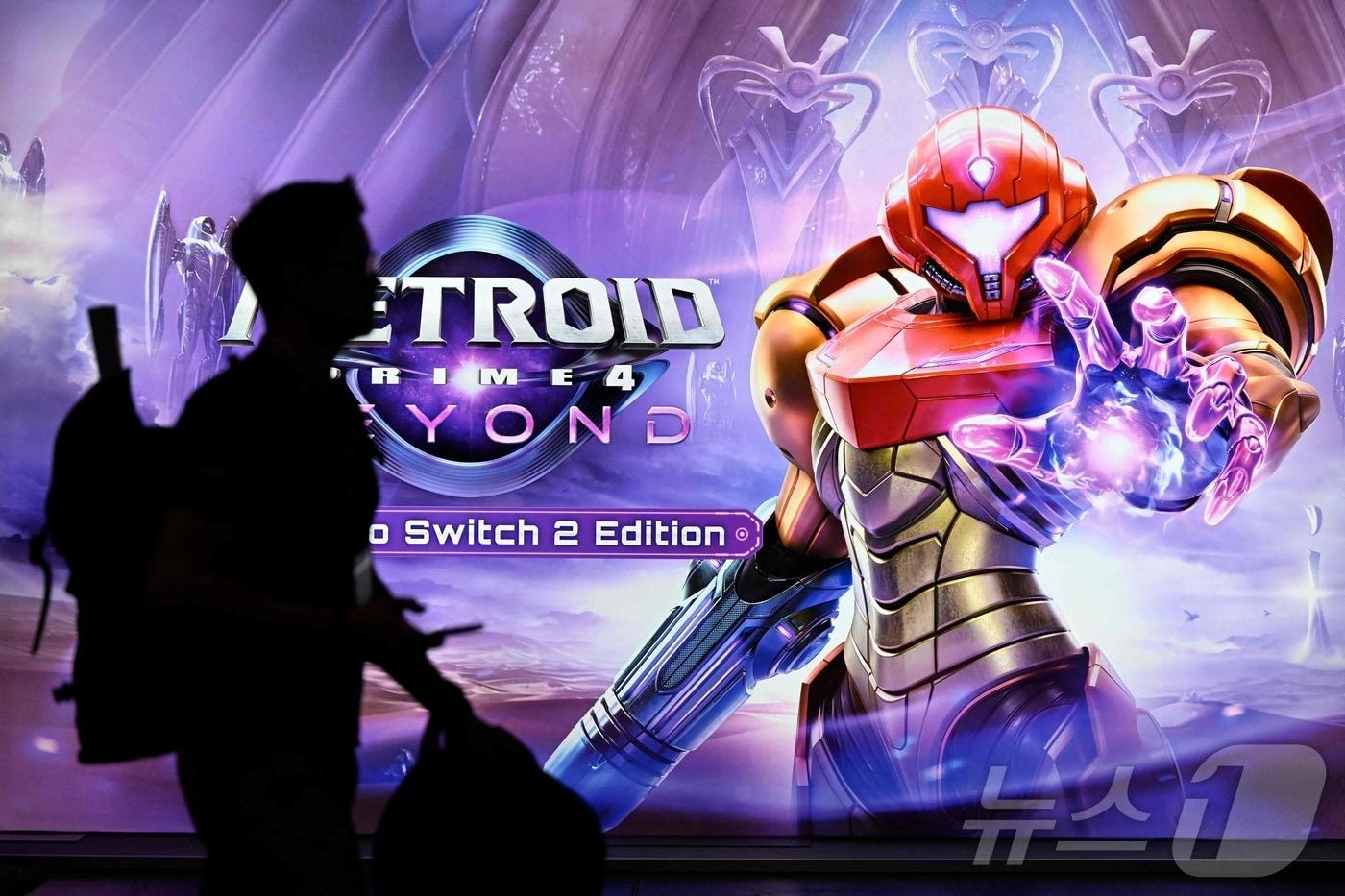 지난 8월 20일 독일 쾰른의 무역박람회센터에서 열린 게임스콤 비디오게임 무역박람회에서 닌텐도 부스에 있는 &#39;메트로이드 프라임4 비욘드 닌텐도 스위치2 에디션&#39; 비디오게임 플래카드를 지나가고 있다. 2025.08.20. ⓒ AFP=뉴스1 ⓒ News1 이정환 기자