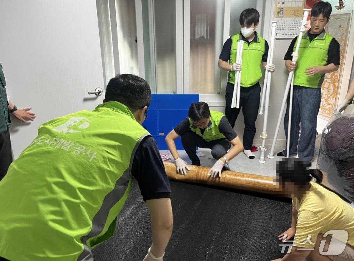 본문 이미지 - 대구도시개발공사 직원들이 취약계층 주거환경 개선사업 일환으로 노후 주택의 장판을 교체하고 있다.&#40;대구도시개발공사 제공, 재판매 및 DB 금지&#41;