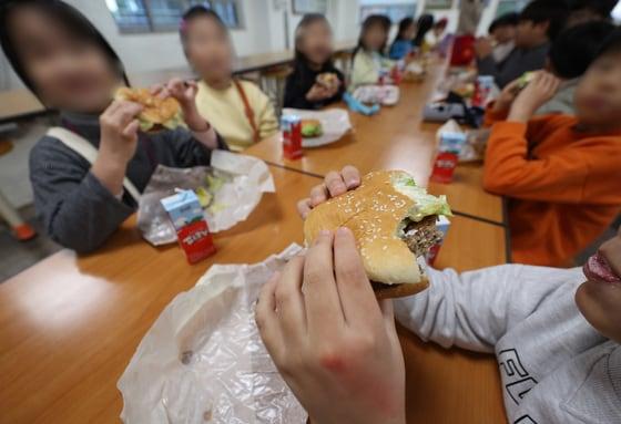 본문 이미지 - 한 초등학교 급식실에서 학생들이 대체식으로 제공된 햄버거를 먹고 있다. 2025.12.5 ⓒ 뉴스1 공정식 기자