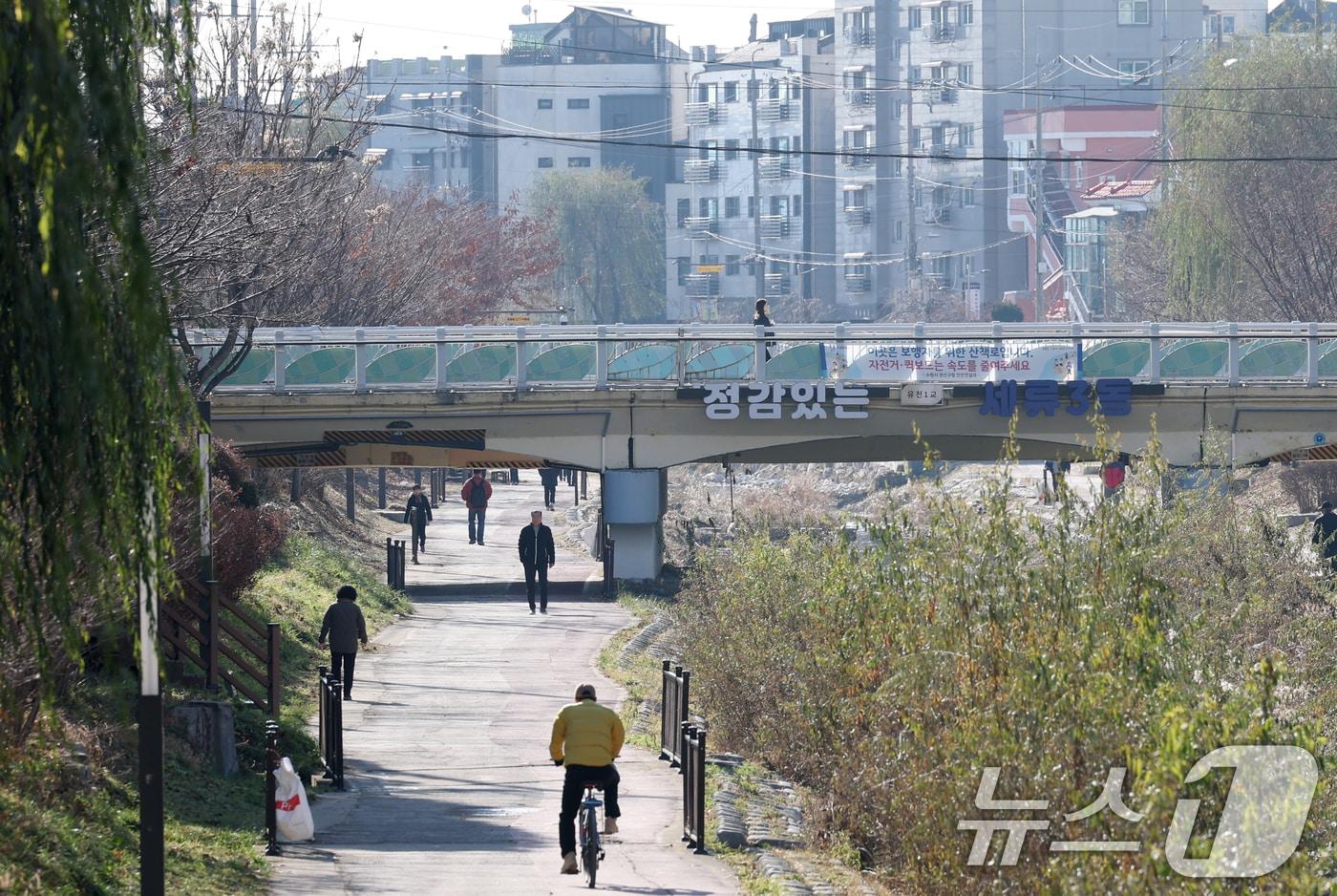 포근한 겨울 날씨를 보인 9일 경기 수원시 권선구 세류천에서 시민들이 산책을 즐기고 있다. 2025.12.9/뉴스1 ⓒ News1 김영운 기자