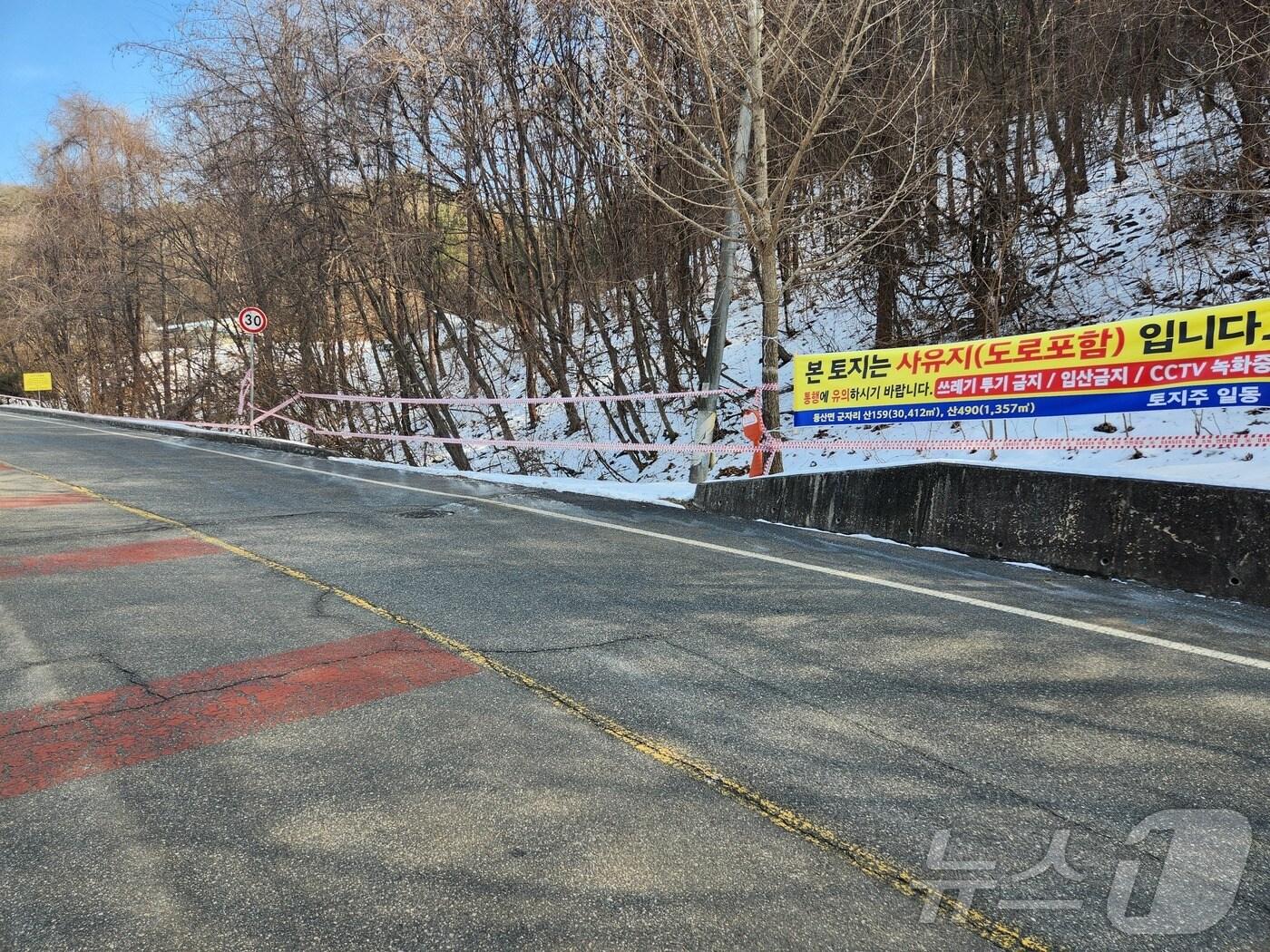 본문 이미지 - 지난 12일 오후 춘천 동산면 군자리에 위치한 공원묘원의 진입로에 해당 구간이 사유지임을 알리는 현수막이 내걸려 있다. 해당 진입로의 일부 구간은 사유지임에도 관리주체인 춘천시는 수년째 매입 등 보상을 해주지 않고 있어 토지주들이 피해를 호소하고 있다. 2025.2.12/뉴스1 이종재기자