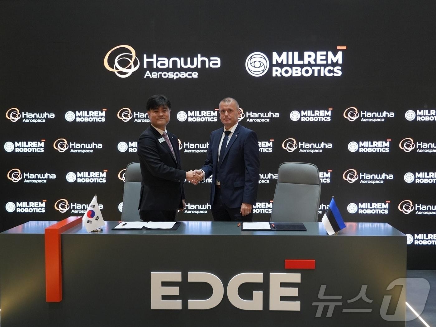 본문 이미지 -  지난 18일 UAE 아부다비에서 진행 중인 &#39;IDEX 2025&#39; 전시회에서 김동현 한화에어로스페이스 LS사업부장&#40;왼쪽&#41;과 쿨다 바라시&#40;Kuldar Väärsi&#41; 밀렘 로보틱스 CEO&#40;오른쪽&#41;가 양사 간 UGV 공동개발 및 전략적 파트너십을 확대하는 양해각서&#40;MOU&#41;를 체결하고 기념사진을 찍고 있다. &#40;한화에어로스페이스 제공&#41;