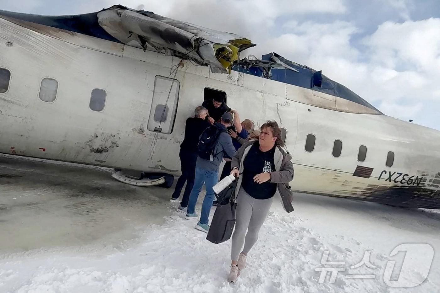 캐나다 토론토 피어슨 국제공항 착륙 중 추락한 델타항공 CRJ-900 여객기에서 승객들이 내리고 있다 ⓒ 로이터=뉴스1