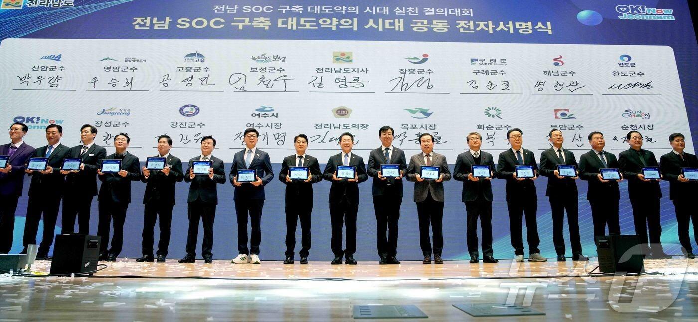 김영록 전라남도지사가 19일 보성 문화예술회관에서 열린 ‘전남 SOC 구축 대도약의 시대 실천 결의대회’에서 시장·군수들과 전남도 미래 100년을 이끌 핵심 SOC사업을 국가계획에 반영하기 위한 공동건의문에 서명을 하고 촬영을 하고 있다.(전남도 제공. 재판매 및 DB금지) 2025.2.19/뉴스1 