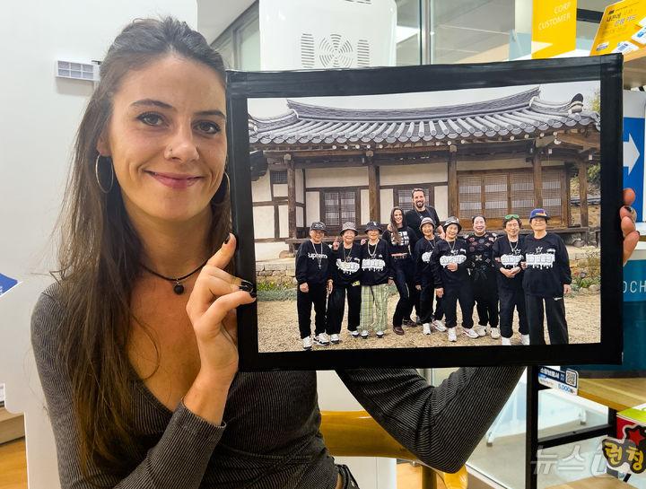 본문 이미지 - 카프리카 감독이 수니와칠공주와 함께 한 사진을 들어보이고 있다 (칠곡군 제공. 재판매 및 DB금지) 2025.02.23/뉴스1