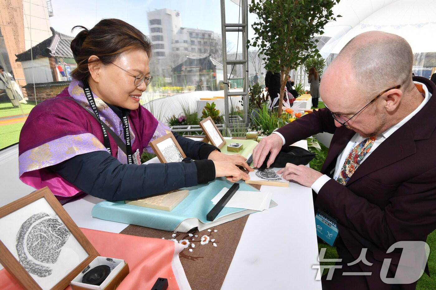 본문 이미지 - APEC 2025 KOREA (SOM1) 고위관리회의 둘째날인 25일 회의장인 경북 경주시 보문단지 경주컨벤션센터(HICO) 야외에 마련된 투명 돔 공연장에서 미국 관계자가 신라의 미소 탁본을 직접 만들어 보고 있다. 이번 회의는 24일부터 다음 달 9일까지 HICO에서 APEC 21개 회원국 대표단 등 2000여명이 28개 회의체를 구성해 총 100여 차례의 회의를 개최한다. 2025.2.25/뉴스1 ⓒ News1 최창호 기자