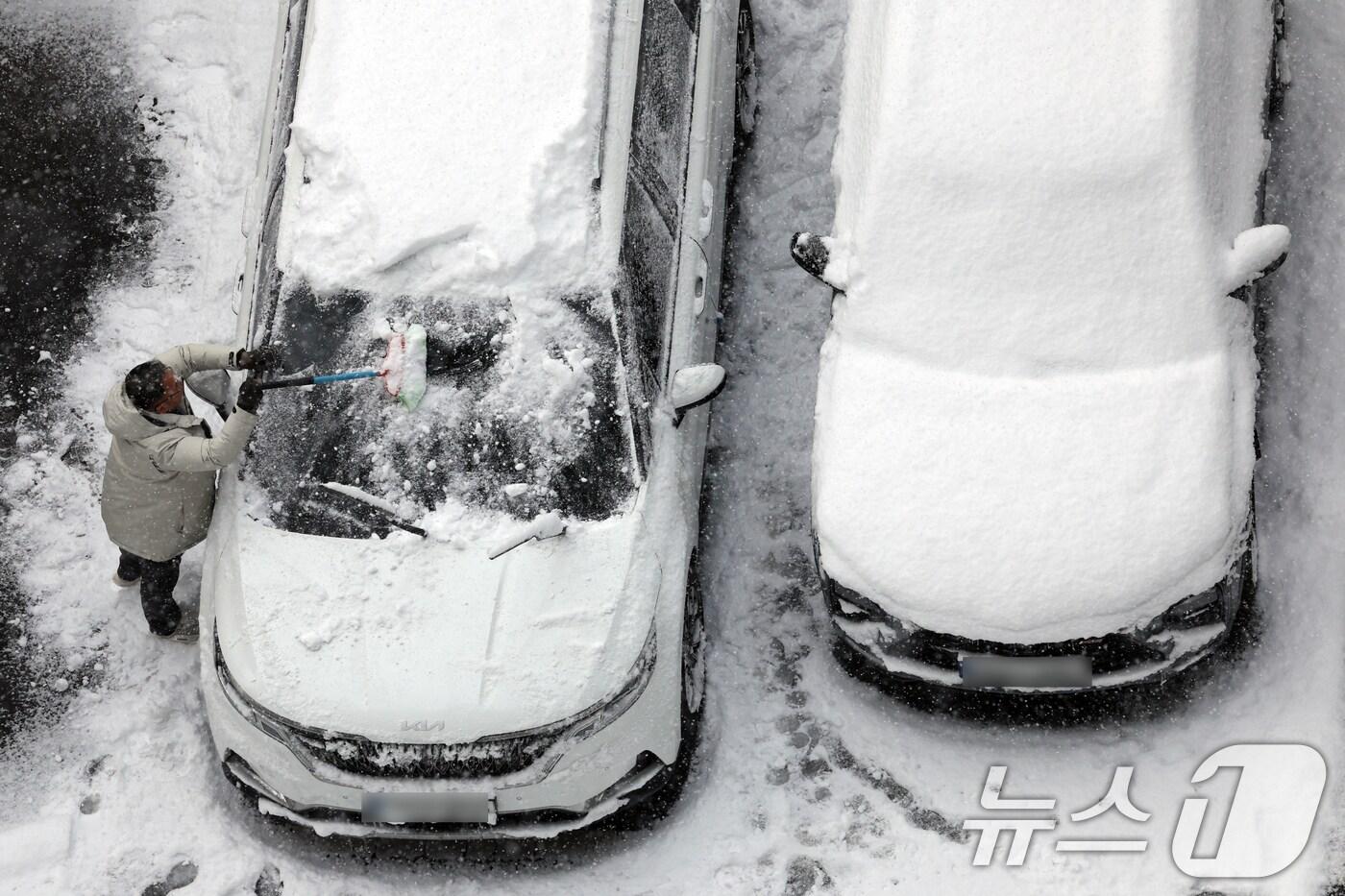 4일 광주 광산구 한 아파트에서 시민이 차에 쌓인 눈을 치우고 있다. 2025.2.4./뉴스1 ⓒ News1 김태성 기자