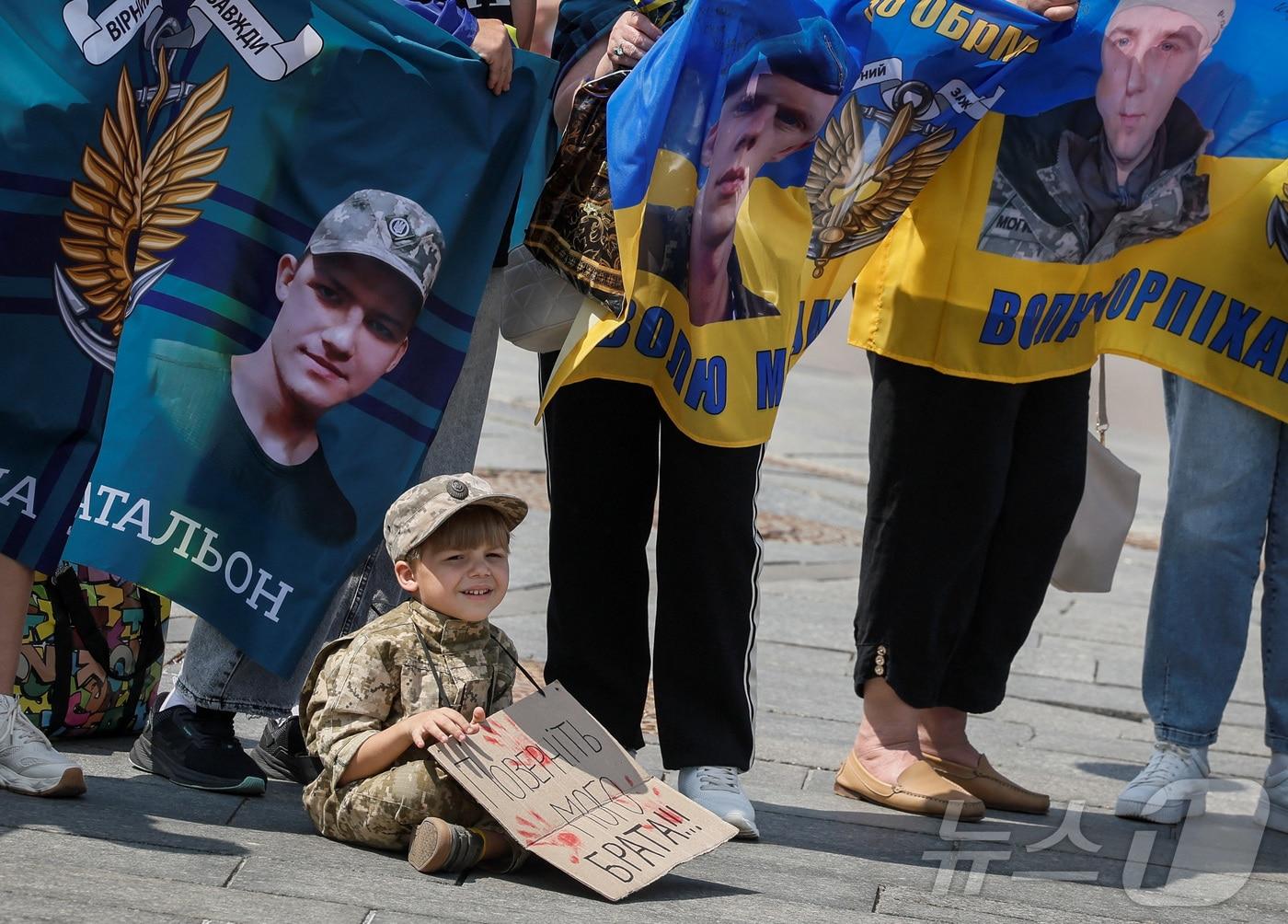 본문 이미지 - 2024년 5월 23일 군복을 입은 소년이 '내 형제를 데려오라'는 문구가 새겨진 현수막을 들고 있다. 2024.05.23 ⓒ 로이터=뉴스1 ⓒ News1 김경민 기자