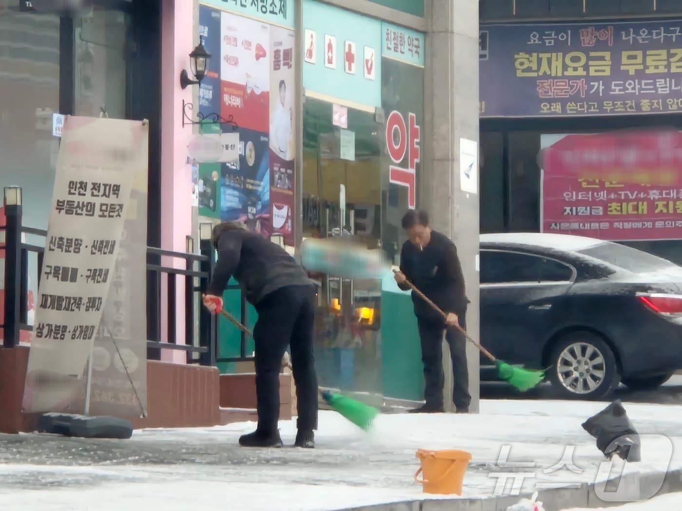 본문 이미지 - 대설주의보가 발효된 7일 오전 인천의 각 상가 관계자들이 빗자루를 들고 밤사이 쌓인 눈을 치우고 있다.