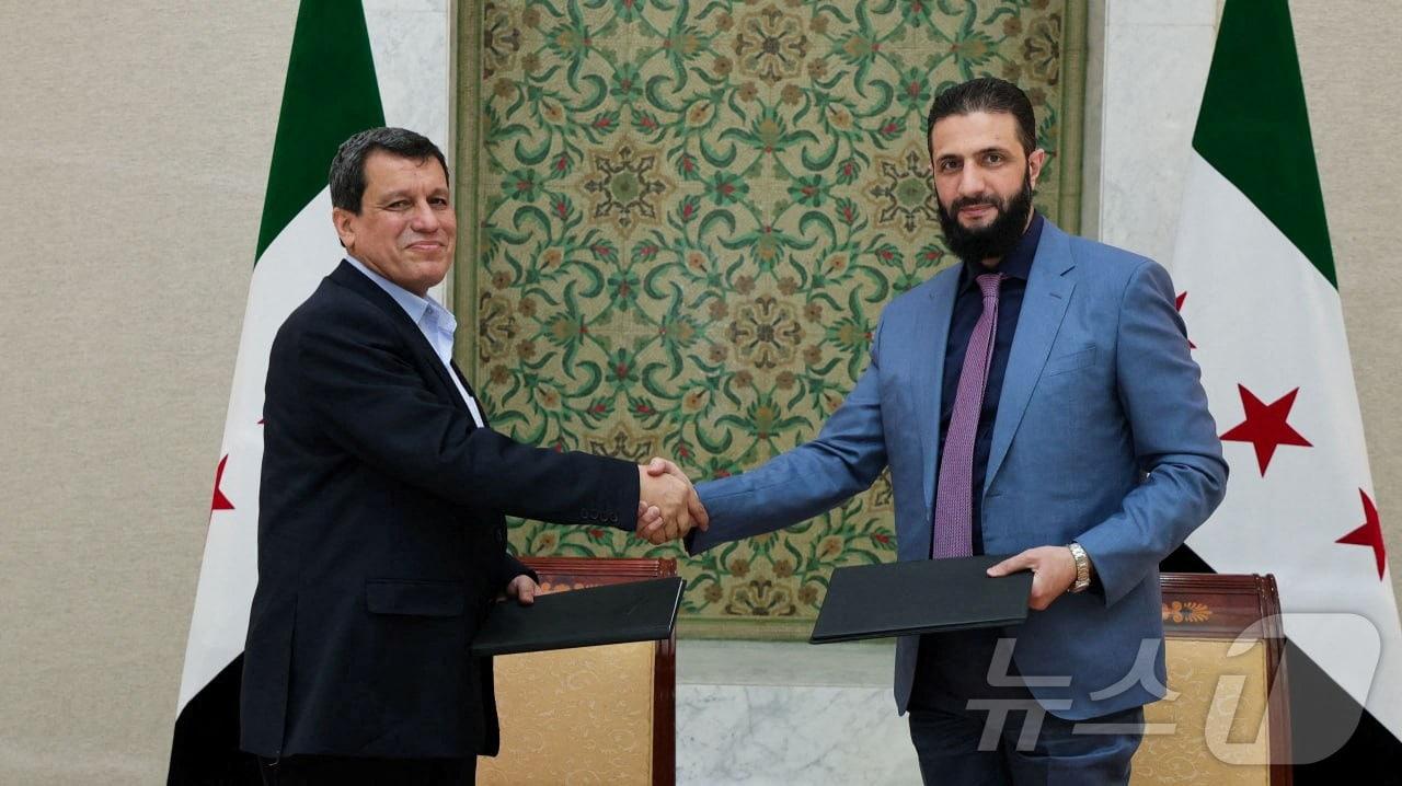 본문 이미지 - 아메드 알샤라 시리아 임시대통령&#40;오른쪽&#41;과 마즐룸 압디 SDF 총사령관은 10일&#40;현지시간&#41; 이같은 합의하고 악수하고 있다. 2025.03.10. ⓒ 로이터=뉴스1