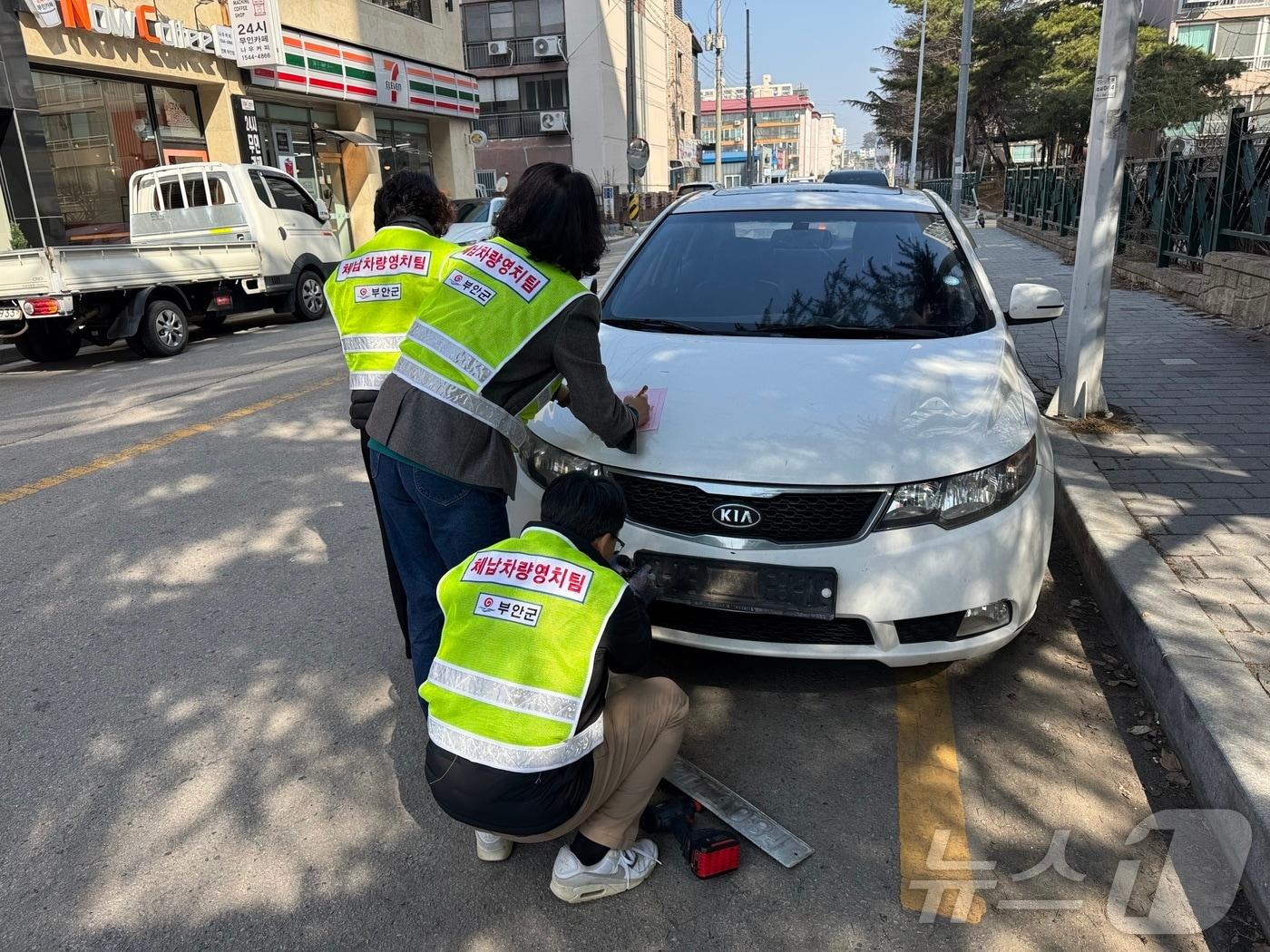 본문 이미지 - 부안군이 건전한 납세문화 조성을 위해 상습·고질 체납차량 번호판 영치 특별반을 운영한다. 단속 공무원이 체납차량의 번호판을 떼어내고 있다.(부안군 제공. 재판매 및 DB금지)