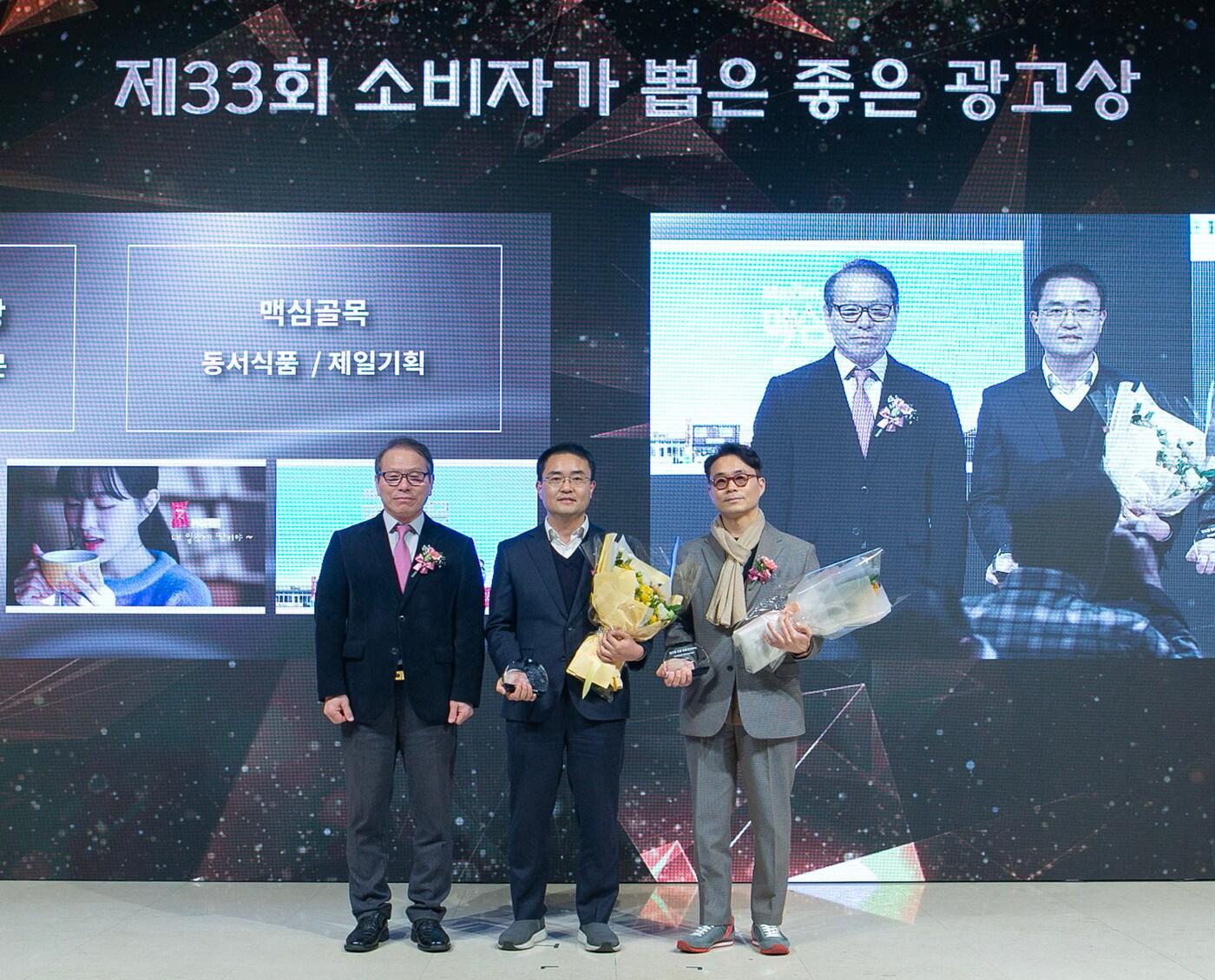 본문 이미지 -  동서식품 '맥심골목'이 13일 개최된 '제33회 소비자가 뽑은 좋은 광고상' 시상식에서 OOH영상 부문 '좋은 광고상'을 수상했다. 사진은 동서식품 마케팅 (가운데)하치수 팀장이 기념 촬영을 하고 있는 모습.(동서식품 제공)