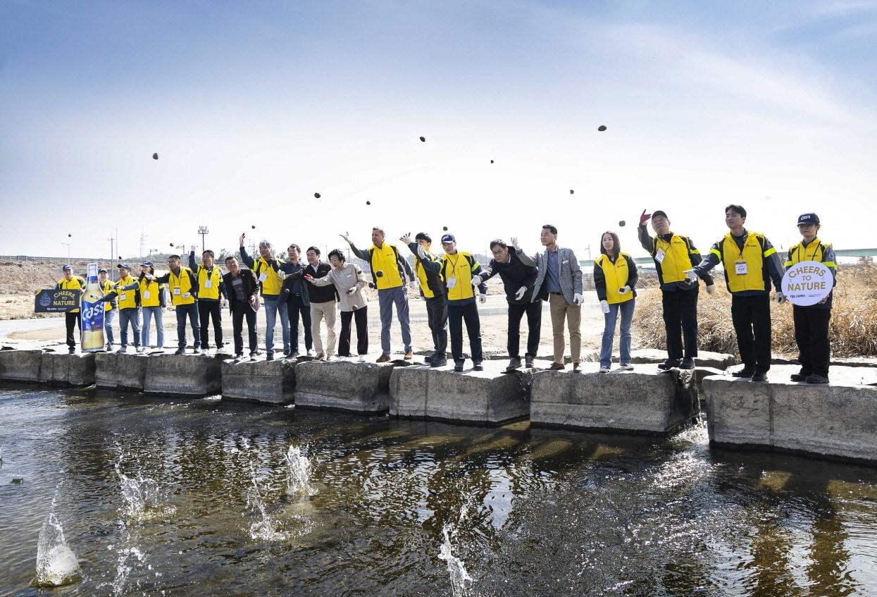 본문 이미지 - 13일 오비맥주 이천공장 임직원들이 이천시청 관계자들과 이천시 복하천에서 &#39;EM 흙공 던지기&#39;를 하며 하천 정화 활동을 펼치고 있는 모습.&#40;오비맥주 제공&#41;