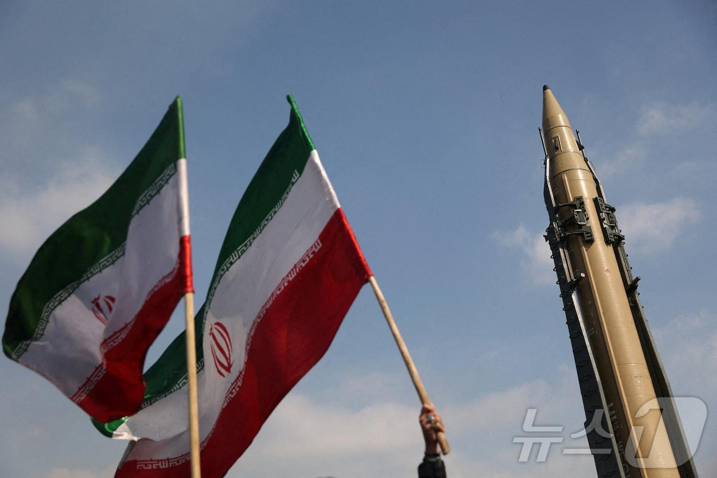 지난 2월 10일(현지시간) 이란 테헤란에서 열린 이슬람 혁명 46주년 기념식에서 전시된 이란 미사일 옆에서 시민들이 이란 국기를 흔들고 있다. ⓒ 로이터=뉴스1 ⓒ News1 류정민 특파원