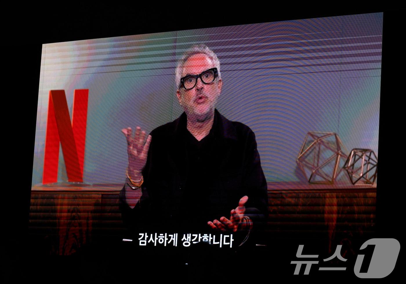 본문 이미지 - 알폰소 쿠아론 이그제큐티브 프로듀서가 18일 서울 마포구 호텔나루 서울 엠갤러리에서 열린 넷플릭스 '계시록'(감독 연상호) 제작보회에서 영상으로 인사말을 하고 있다. '계시록'은 실종 사건의 범인을 단죄하는 것이 신의 계시라 믿는 목사(류준열 분)와 죽은 동생의 환영에 시달리는 실종 사건 담당 형사(신현빈 분)가 각자의 믿음을 쫓으며 벌어지는 이야기를 그린 작품이다. 2025.3.18/뉴스1 ⓒ News1 권현진 기자