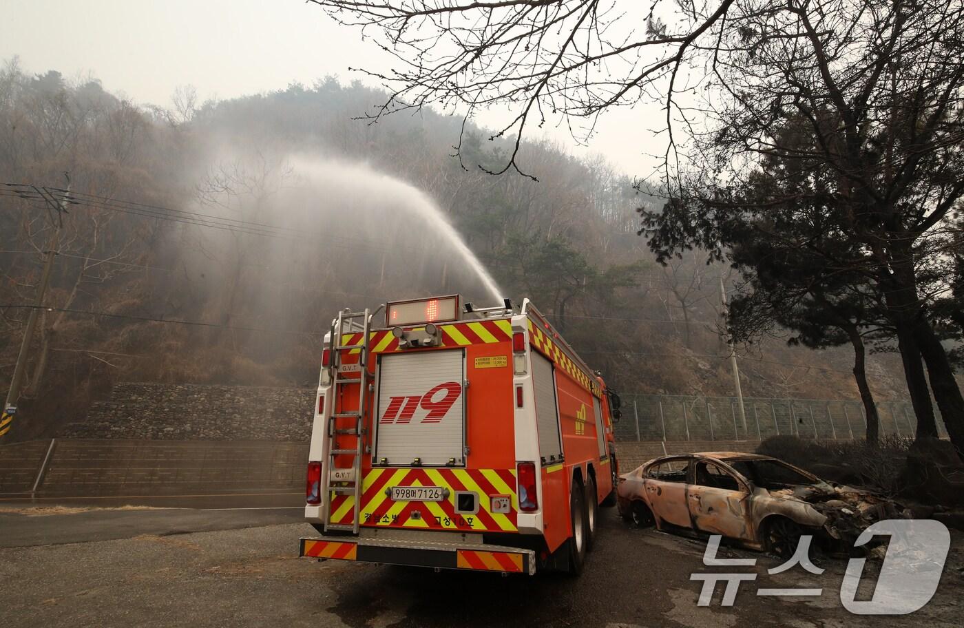 본문 이미지 - 경남 산청 대형 산불이 사흘째로 접어든 23일 오전 산청군 시천면 일대에서 소방이 산불로 인해 전소된 승용차 뒤로 잔불을 정리하고 있다. 2025.3.23/뉴스1 ⓒ News1 윤일지 기자
