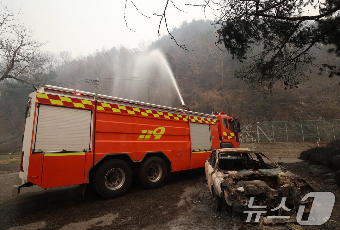 본문 이미지 - 경남 산청 대형 산불이 사흘째로 접어든 23일 오전 산청군 시천면 일대에서 소방이 산불로 인해 전소된 승용차 뒤로 잔불을 정리하고 있다. 2025.3.23/뉴스1 ⓒ News1 윤일지 기자