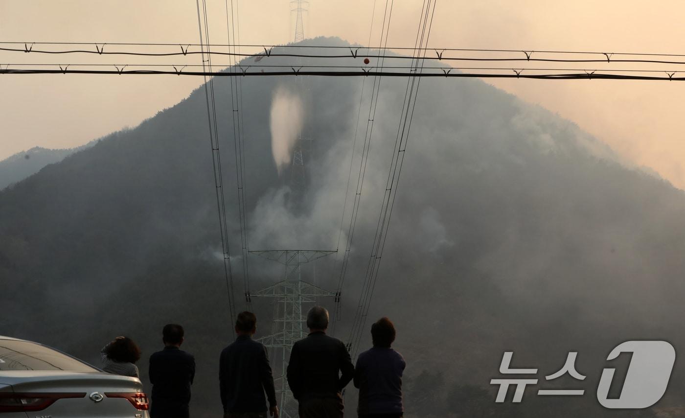 본문 이미지 - 경남 산청 대형 산불이 사흘째로 접어든 23일 오후 산청군 단성면 일대에서 주민들이 산불 연기가 치솟아오르는 모습을 지켜보고 있다. 2025.3.23/뉴스1 ⓒ News1 윤일지 기자