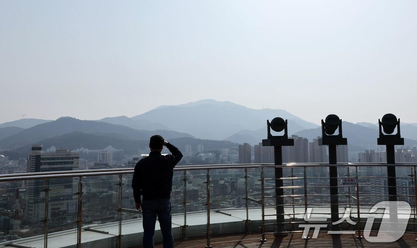 본문 이미지 - 미세먼지 농도가 나쁨을 보인 24일 광주 사직공원 전망대를 찾은 시민이 뿌연 도심을 바라보고 있다. 2025.3.24/뉴스1 ⓒ News1 박지현 기자
