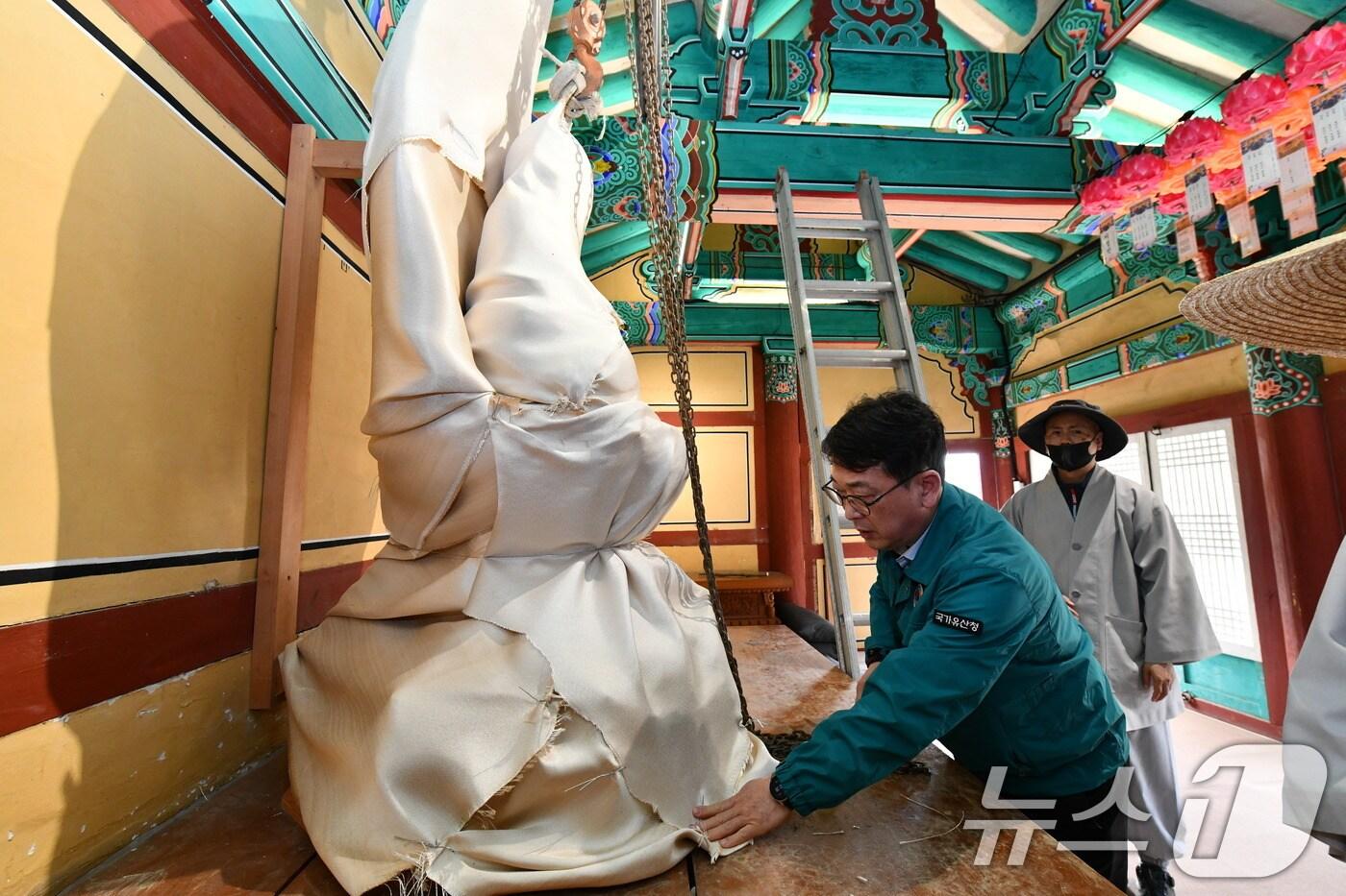 본문 이미지 - 최응천 국가유산청장이 25일 경북 의성군 고운사를 방문, 산불 확산에 대비해 방염포를 씌운 ‘석조여래좌상’을 확인하고 있다. (국가유산청 제공. 재판매 및 DB 금지) 2025.3.25/뉴스1