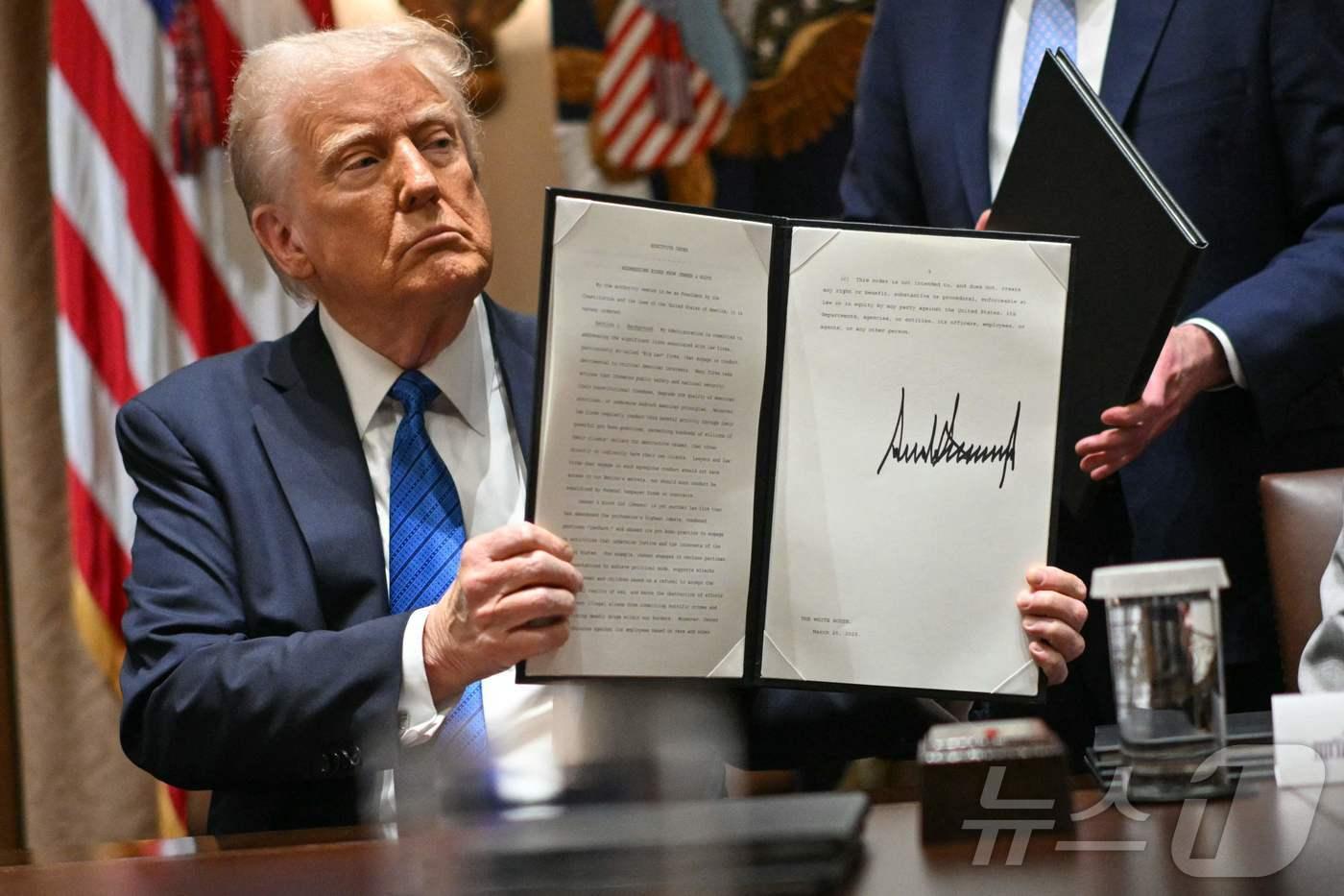 본문 이미지 - 도널드 트럼프 미국 대통령이 25일(현지시간) 워싱턴 백악관에서 서명한 행정명령을 들고 있다. ⓒ AFP=뉴스1
