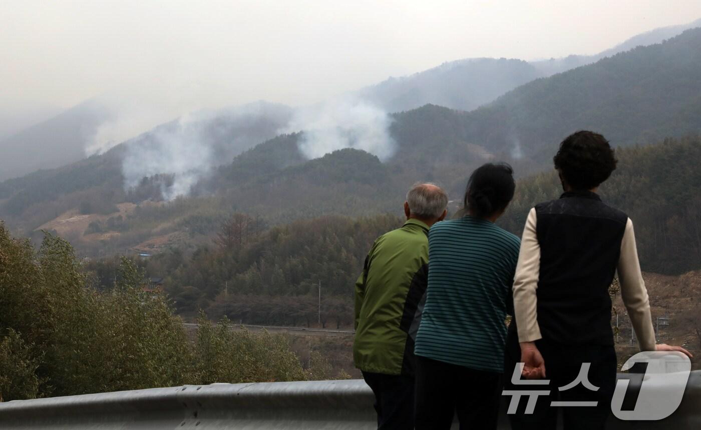 본문 이미지 - 경남 산청·하동 산불 일주일째인 27일 오후 주민들이 지리산과 인접한 산청군 시천면 동당마을 위로 피어오르는 산불 연기를 지켜보고 있다. 산청에는 오후부터 5mm 내외의 적은 비가 예보됐지만 현재 비는 내리지 않고 있다. 2025.3.27/뉴스1 ⓒ News1 윤일지 기자
