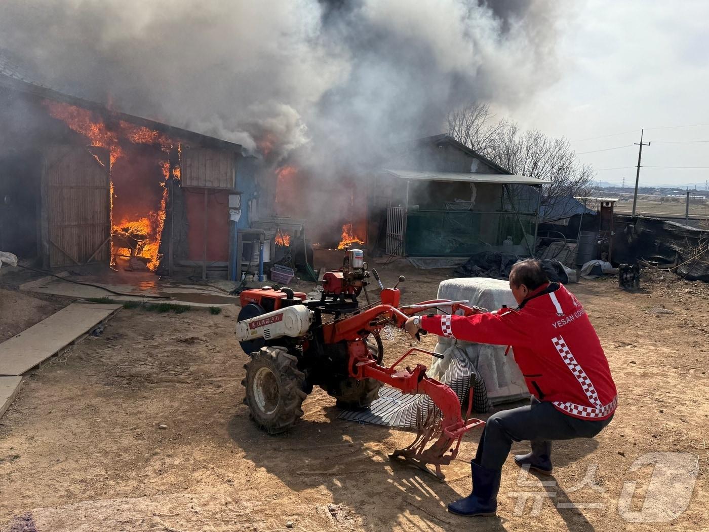 본문 이미지 - 장순관 예산군의회 의장이 화재 현장에서 경운기 등을 안전한 곳으로 옮기고 있다. (예산군의회 제공. 재판매 및 DB금지)/뉴스1