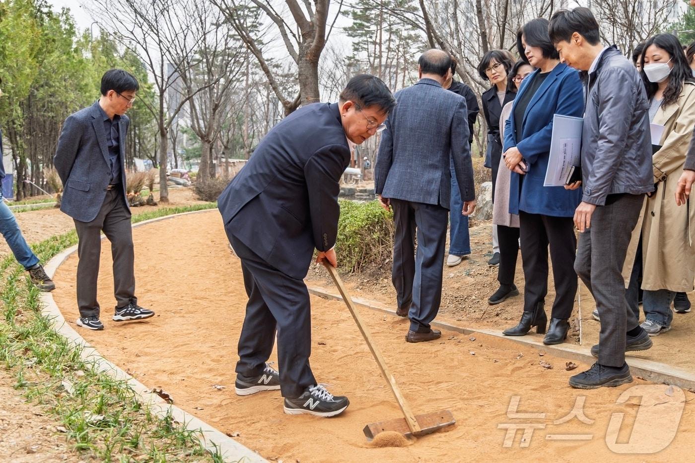 본문 이미지 - 박강수 마포구청장이 부엉이근린공원 맨발 황톳길을 정리하고 있다.(마포구청 제공)