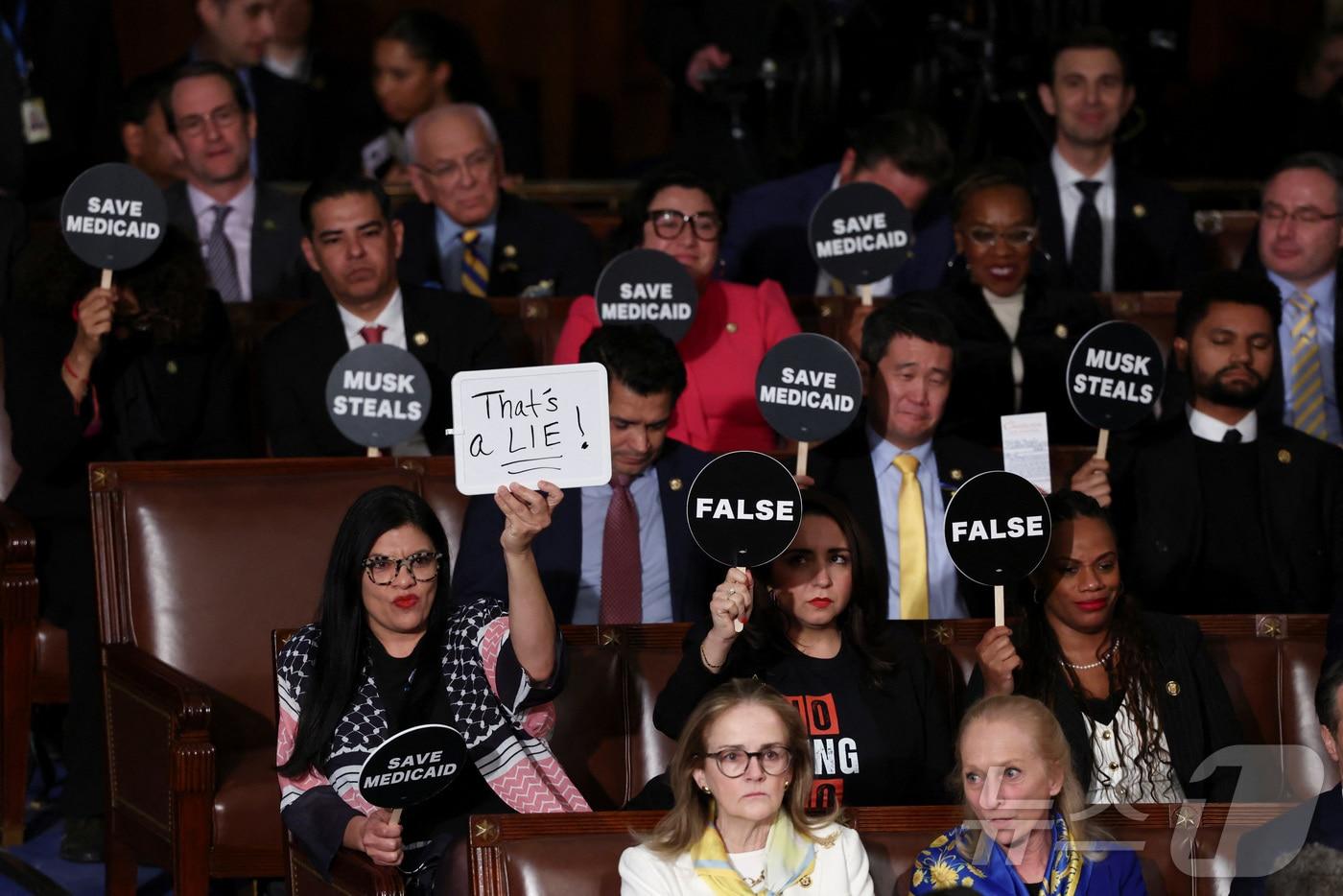 본문 이미지 - 4일(현지시간) 미국 워싱턴DC 의회의사당에서 열린 도널드 트럼프 미국 대통령의 합동의회 연설 도중 민주당 의원들이 "거짓말＂, ＂건강보험을 보장하라＂, ＂틀렸다＂는 등의 문구가 적힌 팻말을 들어보이고 있다. 2025.03.04 ⓒ 로이터=뉴스1