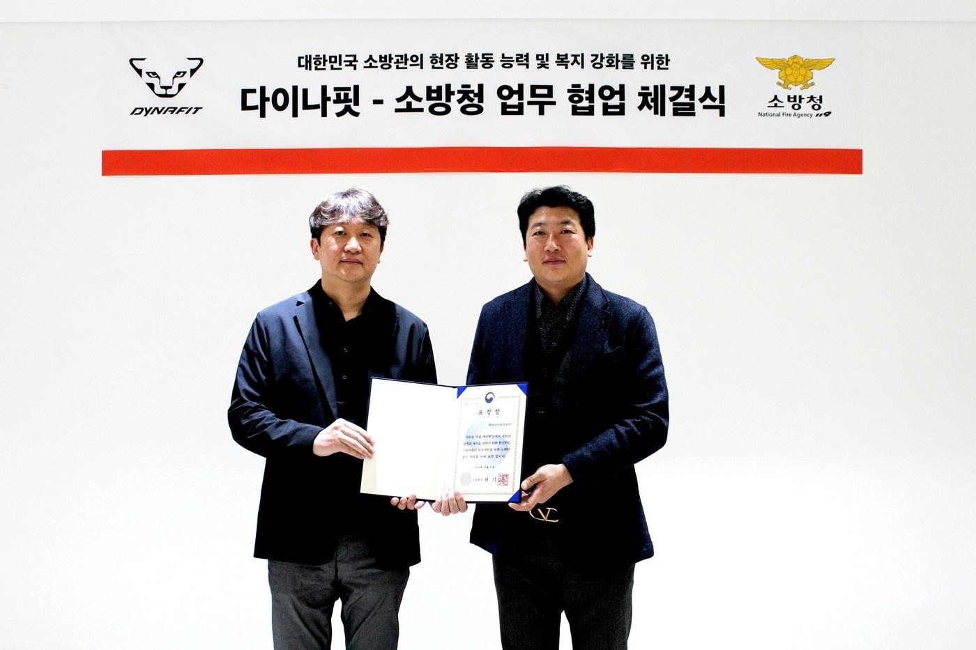 소방청 보건안전담당관 조인담 소방령(오른쪽)과 다이나핏 총괄 본부장 이양엽 상무(왼쪽)가케이투코리아 그룹 사옥에서 열린 협업 체결식에서 기념촬영을 하고 있다.(다이나핏제공)