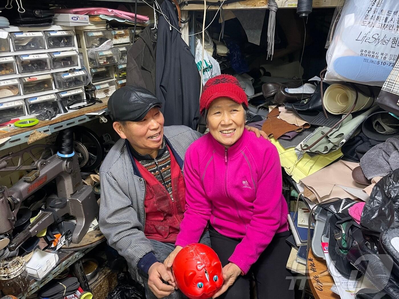 본문 이미지 - 광주 동구 대인동에 위치한 신세계 구두수선에서 수선비용 일부를 19년째 기부하고 있는 김주술·최영심 부부가 돼지저금통을 들어보이고 있다. 2025.3.7/뉴스1