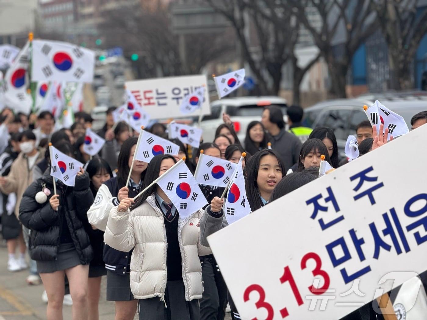 본문 이미지 - 8일 오전 전북 전주시 완산구 신흥고등학교에서 '전주 3·13 만세운동' 재현행사가 열린 가운데 기전여고 학생들이 객사 거리를 지나며 태극기를 흔들고 있다. 2025.3.8/뉴스1 ⓒ News1 장수인 기자