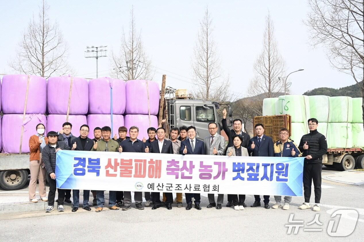 본문 이미지 - 예산 조사료협회  등 관계자들이 경북 산불 피해 축산농가 지원 볏짚 앞에서 기념촬영을 하고 있다. (예산군 제공. 재판매 및 DB금지)/뉴스1