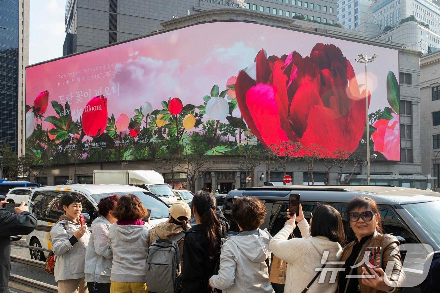본문 이미지 - 신세계스퀘어에서 상영하는 K-컬처 콘텐츠를 보며 즐기는 외국인 관광객 모습. (신세계백화점 제공. 재판매 및 DB 금지) 2025.4.13 ⓒ 뉴스1