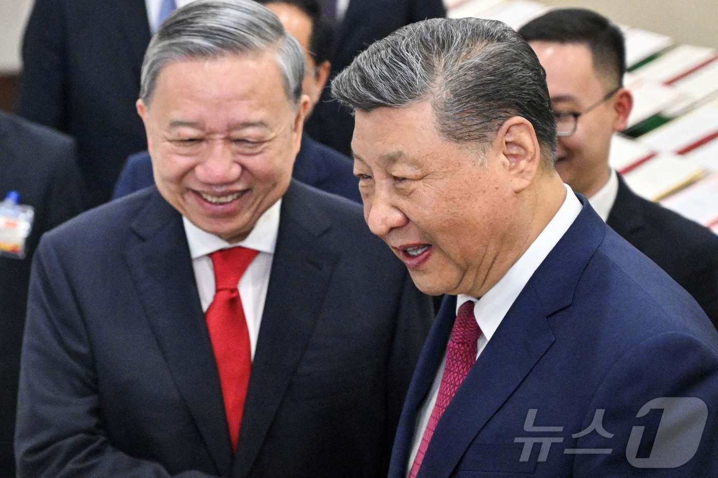 본문 이미지 - 시진핑 중국 국가주석이 14일(현지 시간) 동남아 순방 중 하노이를 방문해 또 럼 베트남 공산당 서기장과 양국간 협약서 사본들을 둘러 보며 악수를 하고 있다. 2025.04.15 ⓒ AFP=뉴스1 ⓒ News1 우동명 기자