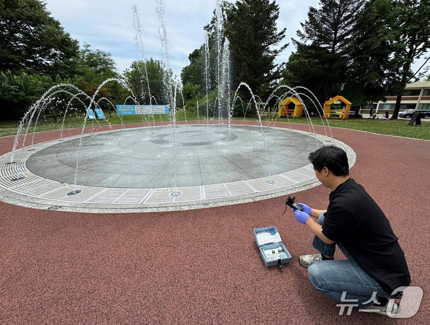 본문 이미지 - 한강청 측정분석과 직원이 지난해 6월 25일 수원시 경기상상캠퍼스 물놀이형 수경시설에서 수질 측정을 하고 있는 모습.(한강청 제공)
