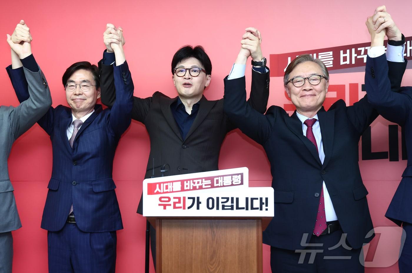 한동훈 국민의힘 대선 경선 후보가 18일 서울 여의도에 마련된 국민먼저캠프 사무실에서 열린 캠프 인사 발표 기자회견에서 최재형&#40;오른쪽&#41;, 조경태 공동선대위원장과 손을 맞잡고 기념촬영을 하고 있다. 2025.4.18/뉴스1 ⓒ News1 김민지 기자