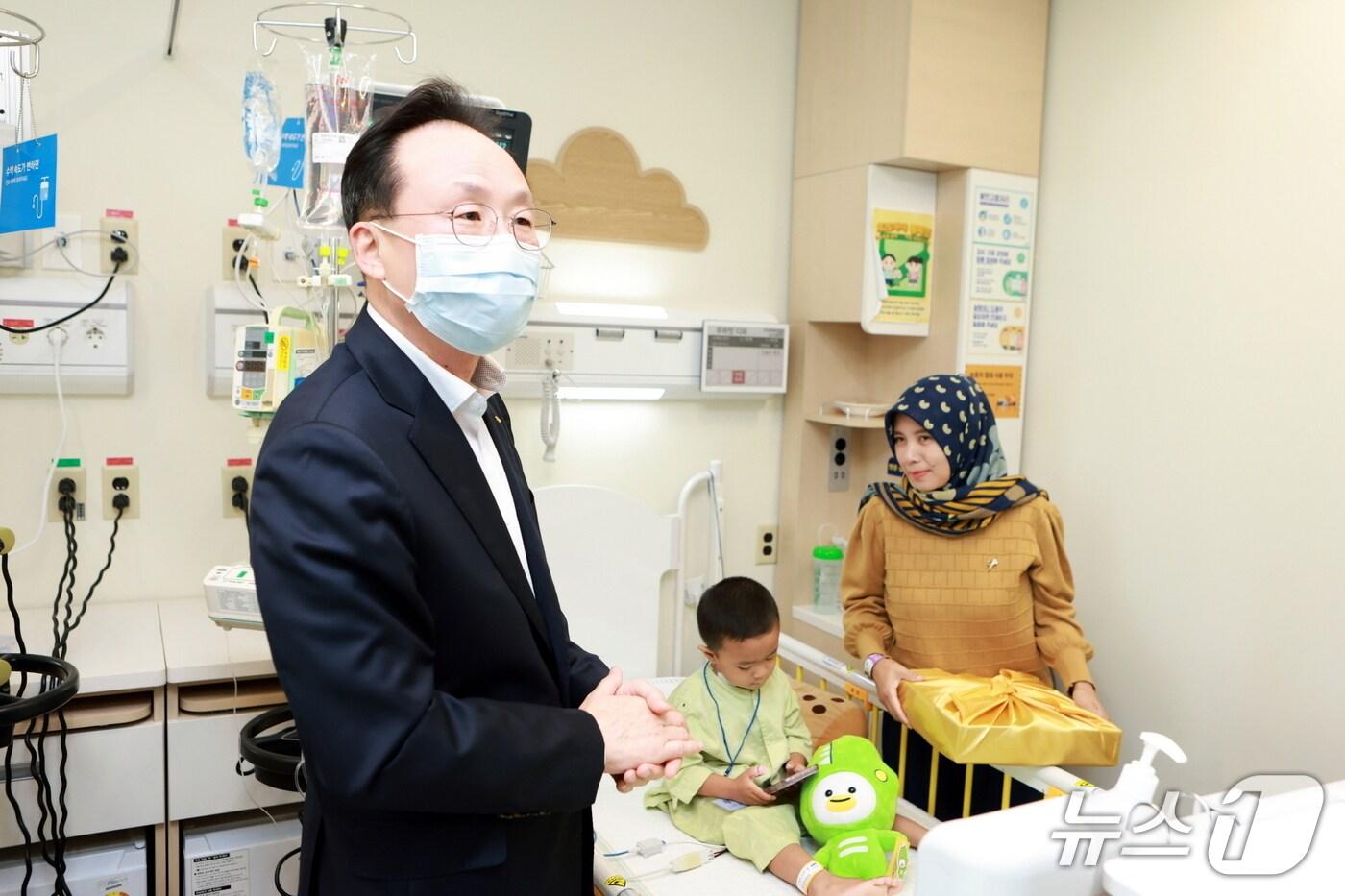23일 서울 강남구 삼성서울병원 소아청소년과 병동에서  이환주 국민은행장이 심장병 수술을 마치고 회복 중인 인도네시아 아동을 만나 선물을 전달하고 있다.