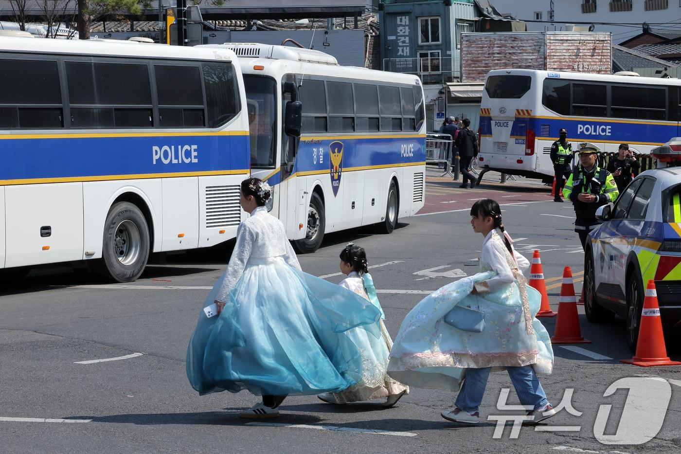 윤석열 대통령 탄핵심판 선고를 하루 앞둔 3일 서울 종로구 재동 헌법재판소 주위로 경찰버스가 겹겹이 세워지는 가운데 한복을 입은 외국인 관광객 가족이 길을 건너고 있다. 2025.4.3/뉴스1 ⓒ News1 박정호 기자