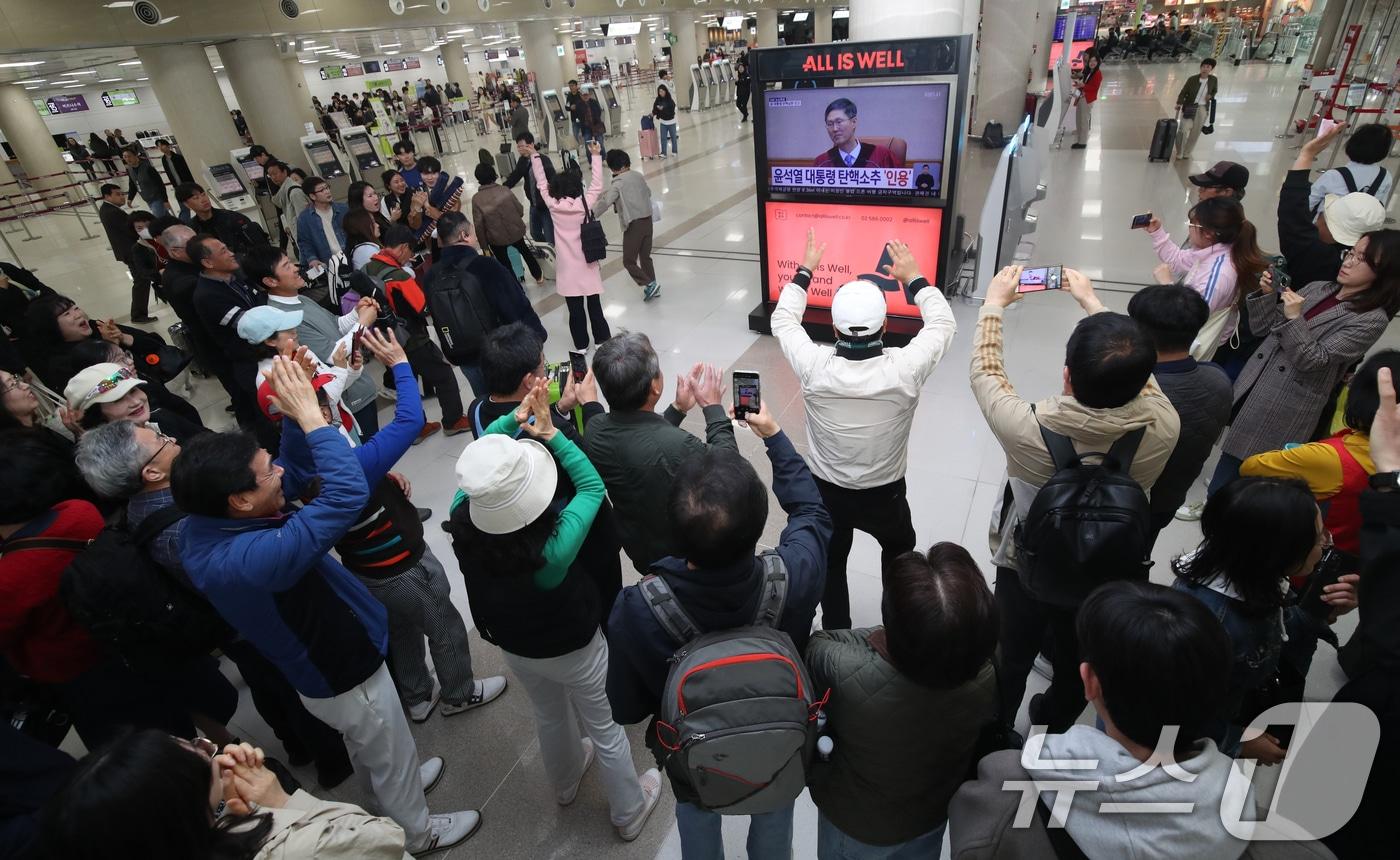 4일 오전 제주국제공항 국내선 출발장에서 관광객과 도민들이 윤석열 대통령의 탄핵심판 선고 TV 생중계를 지켜보다 파면이 결정되자 환호하고 있다. 이날 헌법재판소는 재판관 전원 일치 의견으로 윤 대통령 파면을 결정했다. 2025.4.4/뉴스1 ⓒ News1 오현지 기자