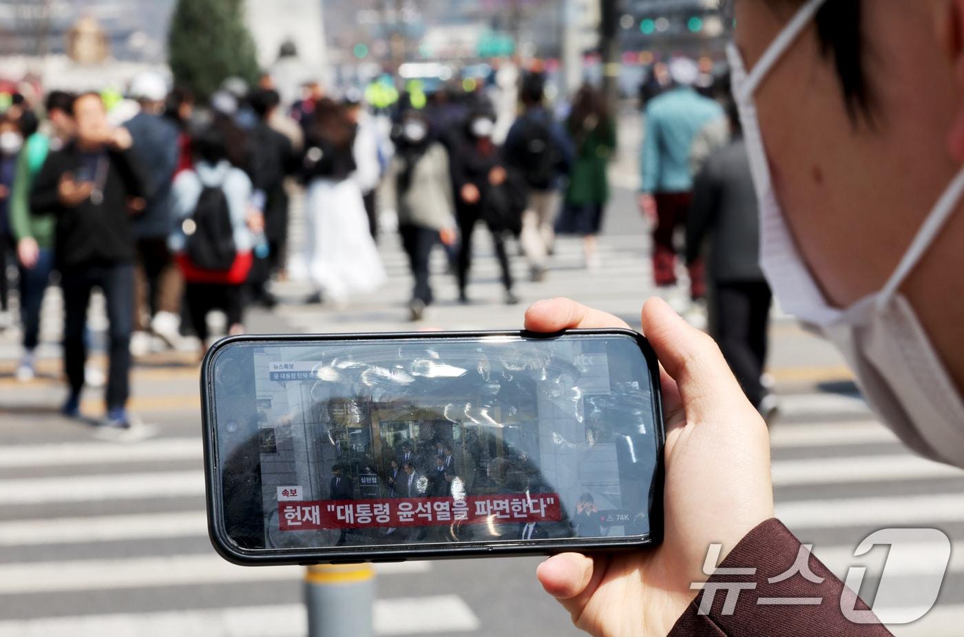 윤석열 대통령 탄핵심판 선고일인 4일 서울 중구 세종대로사거리에서 시민이 대통령 파면 인용 생중계를 시청하고 있다. 이날 헌법재판소는 재판관 전원 일치 의견으로 윤 대통령 파면을 결정했다. 2025.4.4/뉴스1 ⓒ News1 장수영 기자