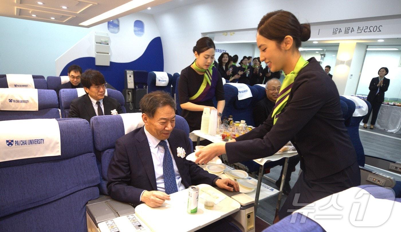 김욱 배재대 총장이 4일 배재대 제2 항공모형비행실습실 개관식에서 객실 서비스 실습에 응하고 있다. (배재대 제공.재판매 및 DB금지)/뉴스1