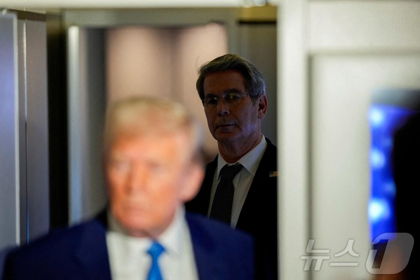 도널드 트럼프 미국 대통령이 2025 년 4월 6일, 메릴랜드 주 앤드류스 공군기지로 비행하는 동안 에어포스원에 탑승한 언론인들과 대화를 나누는 것을 스콧 베선트 재무부 장관이 바라보고 있다.2025.04.06. ⓒ 로이터=뉴스1