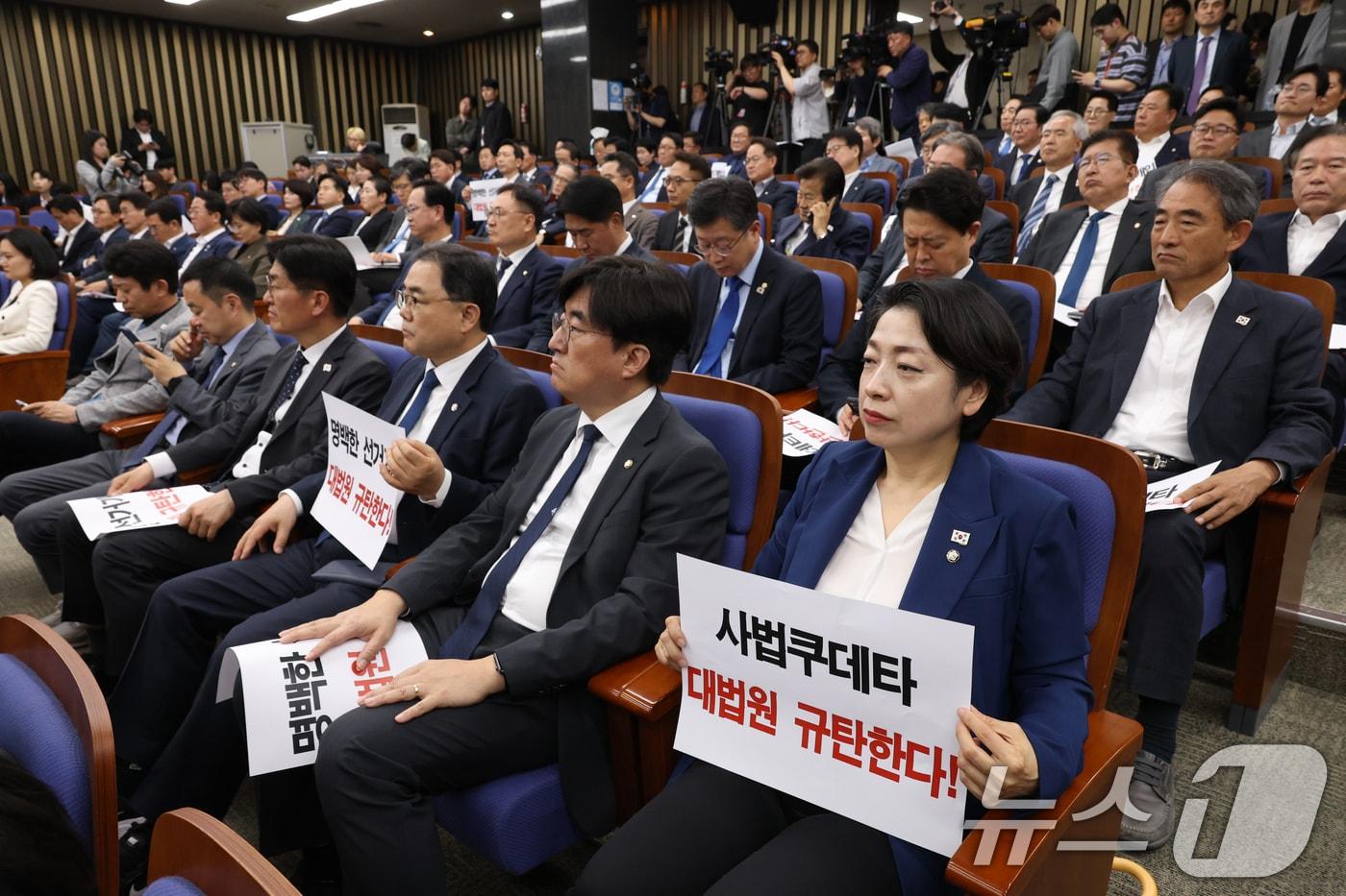 1일 오후 서울 여의도 국회에서 열린 더불어민주당 긴급 의원총회에서 의원들이 이재명 대통령 후보의 공직선거법 위반 혐의에 대해 대법원이 유죄 취지의 파기 환송 결정한 것을 규탄하는 피켓을 들고 있다. 2025.5.1/뉴스1 ⓒ News1 이광호 기자