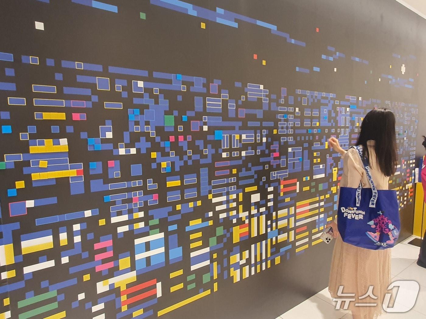 본문 이미지 - 30일 서울 소공동 롯데백화점 에비뉴엘에서 한 고객이 주재범 작가의 고객 참여형 픽셀 아트를 체험하고 있다.